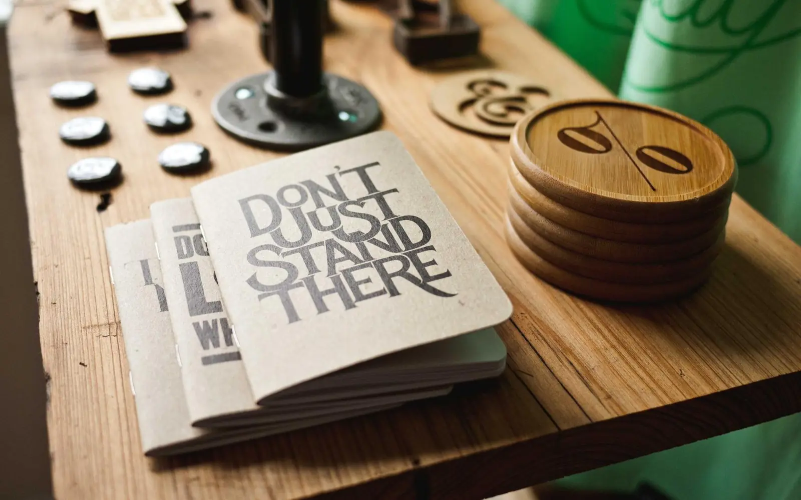 Wooden coasters, a printed notebook and desk tools on a workbench
