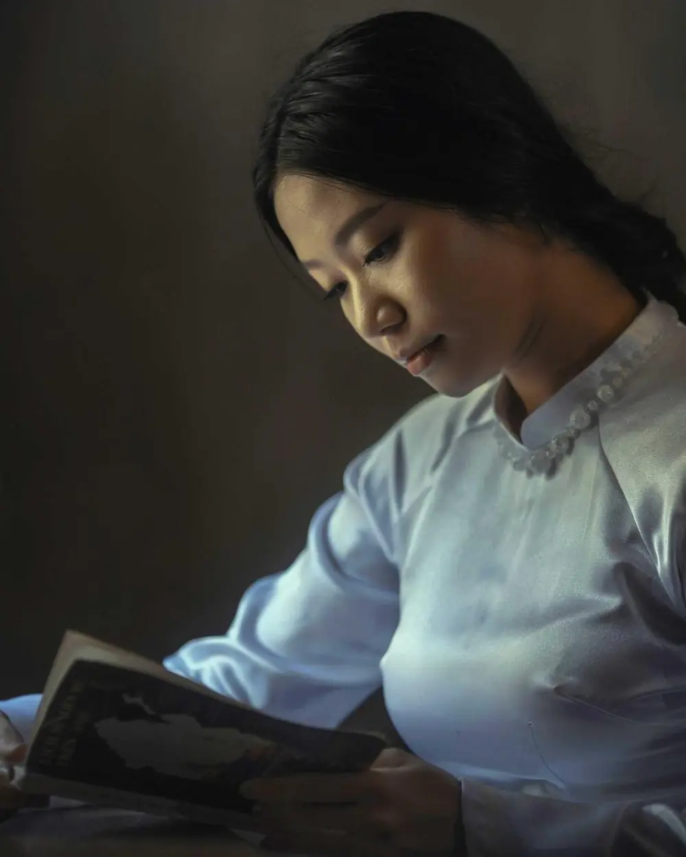 Woman reading a book at a table in soft light