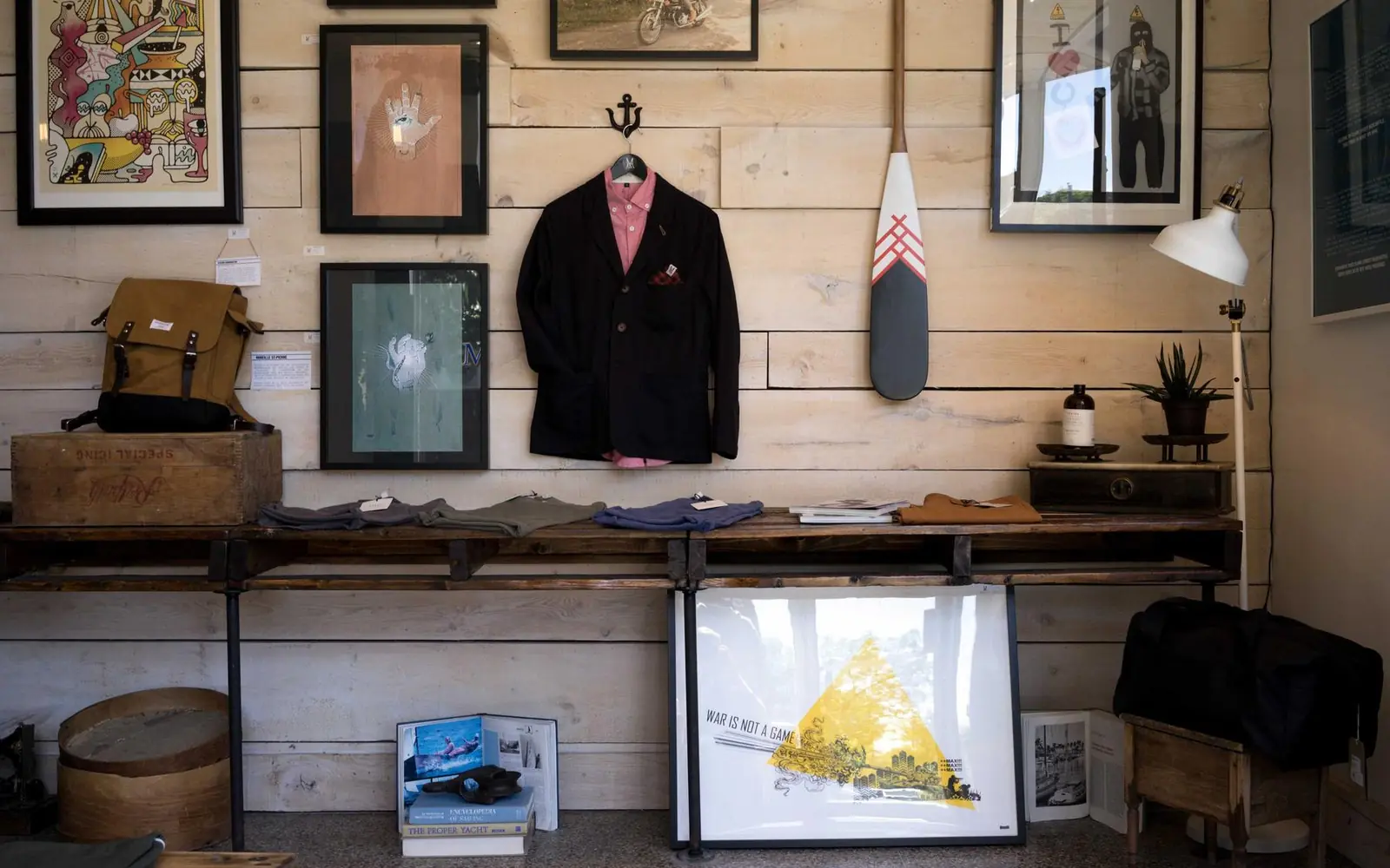 Studio wall with framed prints, shelves and a desk lit by a lamp