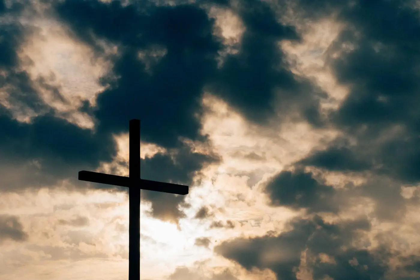 Silhouette of a cross against a cloudy sky
