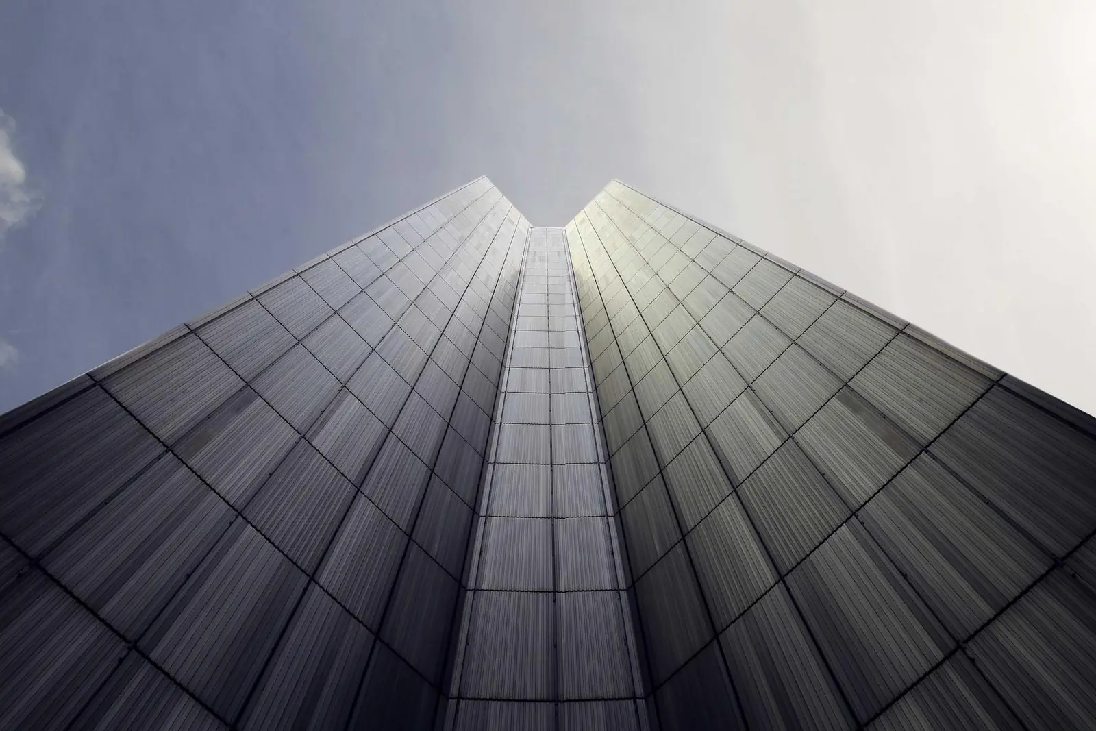 Glass office tower seen from below against a pale sky