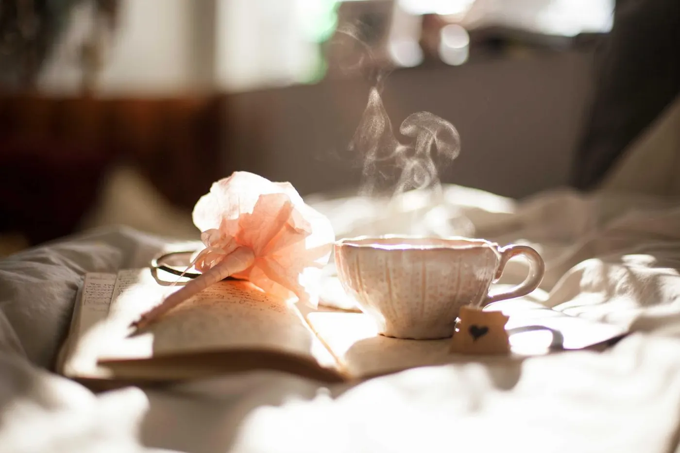 Steaming cup of tea beside an open book